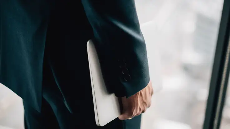 En person går med computer under armen