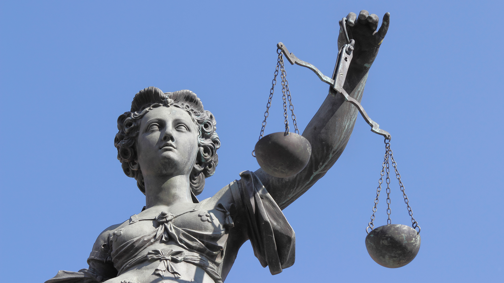 Billede af en statue af Justitia mod en blå himmel i Frankfurt i Tyskland.